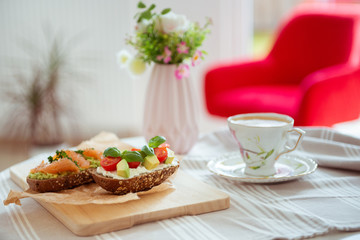 Wholegrain toast with avocado, tomato and salmon on wooden cutting board