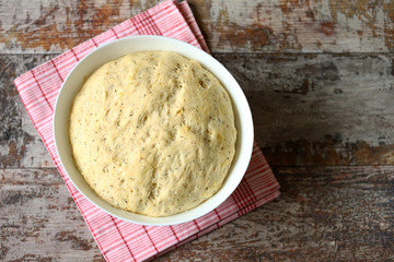 Yeast dough in a bowl. Homemade dough with herbs for bread or pizza. Baking at home.