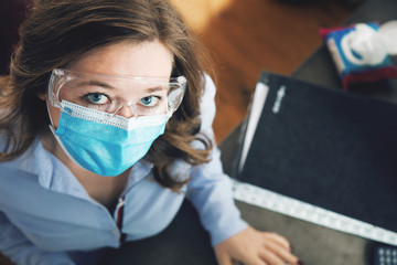 Frau mit Atemschutz maske arbeitet im Büro oder in Home office. Corona virus konzept.