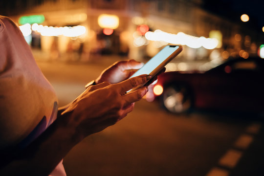 Hands of woman holding smartphone at night, close-up