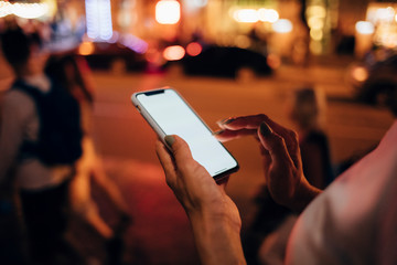 Hands of woman holding smartphone at night, close-up