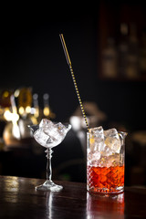 Manhattan cocktail on dark wooden bar in preparation