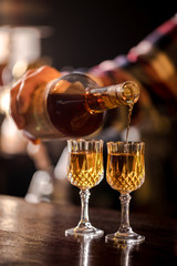 the bartender pours the bourbon into the glasses