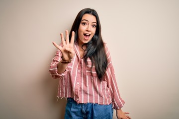Young brunette woman wearing casual striped shirt over isolated background showing and pointing up with fingers number four while smiling confident and happy.