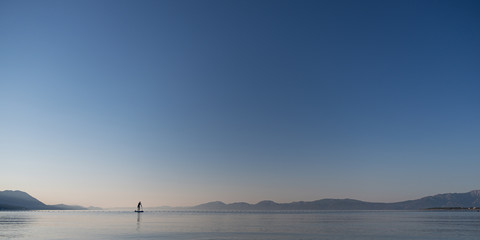 Woman paddling on sup board on calm morning sea
