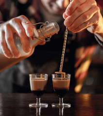 bartender prepares liqueur coffee shots at the bar