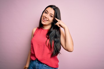 Fototapeta premium Young brunette woman wearing casual summer shirt over pink isolated background Smiling pointing to head with one finger, great idea or thought, good memory