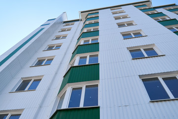 facade of a new multi-storey building with white and green metal siding, many Windows