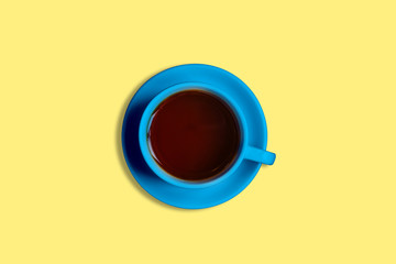 Blue cup with tea on a yellow background. Fragrant hot tea. Top view, minimalism.