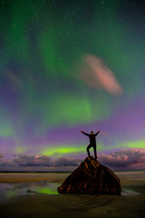 people on the beach and aurora in norway, lofoten islands