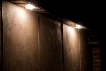 Two large pot lights illuminating a concrete wall in the dark. Illuminated blank building wall at night.
