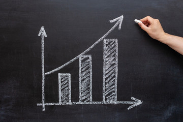 businessman draws market growth chart on chalkboard