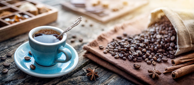 A cup of aromatic black coffee and coffee beans on the table. Morning Coffee Espresso for breakfast in a beautiful blue cup.
