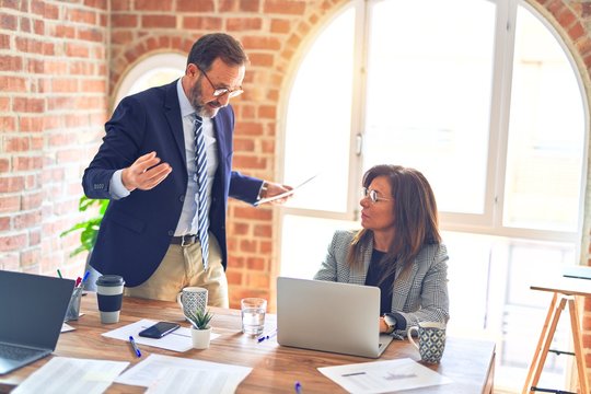 Two middle age business workers working together. Man bullying woman at the office