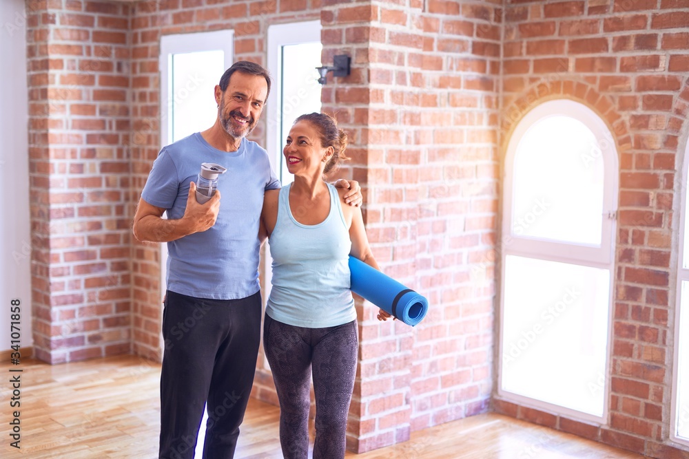 Sticker middle age beautiful sporty couple smiling happy. standing with smile on face hugging and holding ma