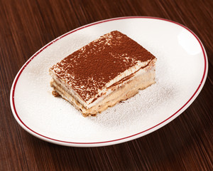 Tiramisu. Original recipe of Italian dessert with cacao powder on top. Authentic Italian cuisine. Wooden table