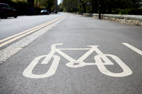 bicycle road sign painted on cycle lane on edge of road marked with double yellow lines.
