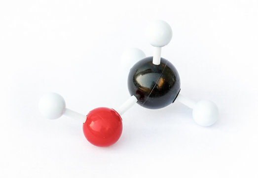 Plastic ball-and-stick model of a methanol molecule (chemical formula CH3OH) on a white background. 