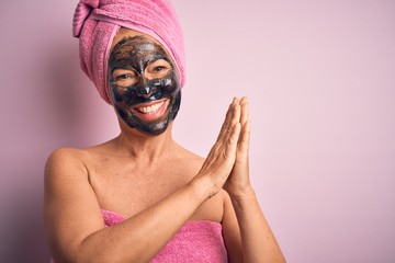 Middle age brunette woman wearing beauty black face mask over isolated pink background clapping and applauding happy and joyful, smiling proud hands together