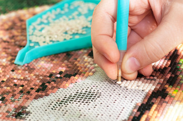 Collecting diamond embroidery, diamond mosaic. Colored crystals. Needlework. Creation. CloseUp.