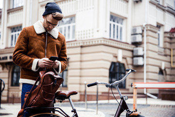 Calm man with smartphone and his bicycle in the city stock photo