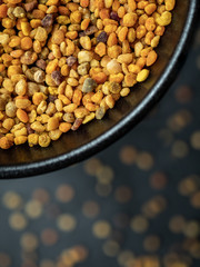 Bee pollen grains in black bowl. Natural medicine to avoid infl