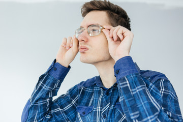 Visually impaired young man looks through glasses. Man in a blue shirt