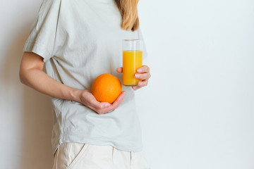 Girl holds a glass of orange juice in her hands. Fresh natural orange juice. Vitamin drink for breakfast. Healthy lifestyle, organic diet. Refreshment after morning fitness. Enjoy delicious beverage