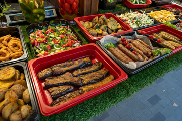 outdoor fast food street food, fried potatoes and boiled corn, cheese rings, fresh vegetable salad, fried eggplant, outdoor fast food street