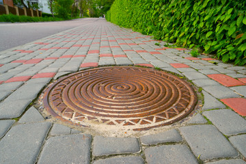 metal round sewer hatch on the sidewalk