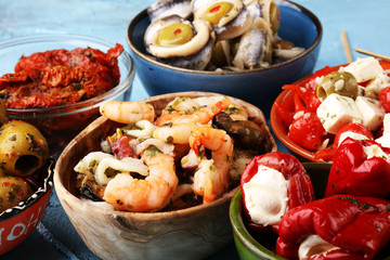 Antipasti Appetizer sweet cherry peppers stuffed with soft cheese feta, olives with oil. Seafood and anchovies with olives and dried tomatoes in oil