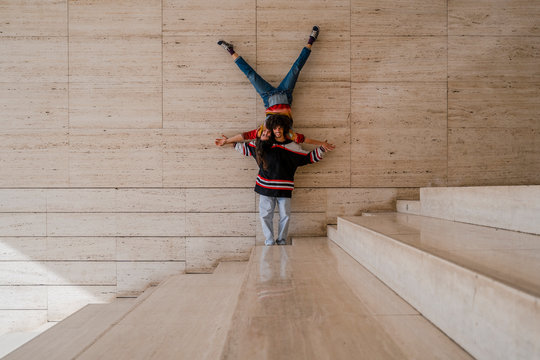 Couple of dancers on a wall, woman balancing upside down on man