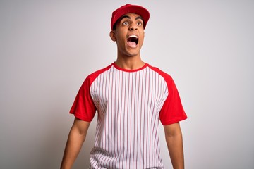Young handsome african american sportsman wearing striped baseball t-shirt and cap angry and mad...