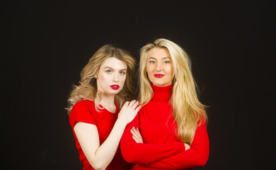 Friends forever. Two cute lovely girl friends in red posing with smile on dark background.