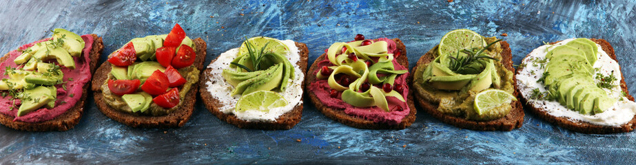Avocado sandwich. Variation of healthy rye breakfast sandwiches with avocado and toppings like tomato and pomegranate