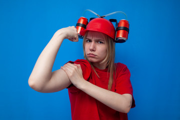 serious girl fan shows biceps arms and looks at the camera, a strong cheerleader in red uniform on a blue background