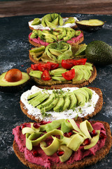 Avocado sandwich. Variation of healthy rye breakfast sandwiches with avocado and toppings like tomato and pomegranate