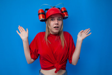 surprised funny girl fan in red clothes and with a beer hat on a blue background shrugs, fan shrugs