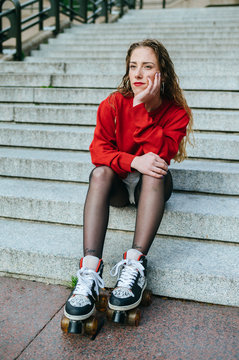 Young woman with roller skates sitting on stairs