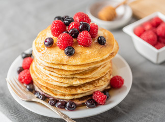 Sweet homemade pancakes with fruits on white plate.