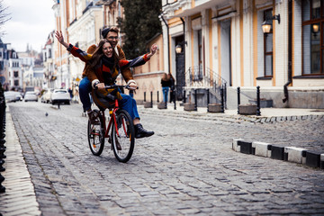 Happy woman on the bike with boyfriend putting hands up