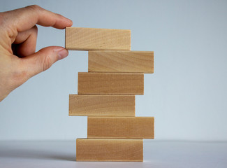 Concept of building success foundation. Women hand put wooden blocks on the stack of wooden blocks.