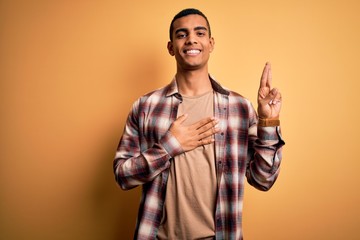 Young handsome african american man wearing casual shirt standing over yellow background smiling...