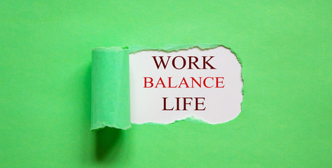 The text work balance life appearing behind torn green paper.