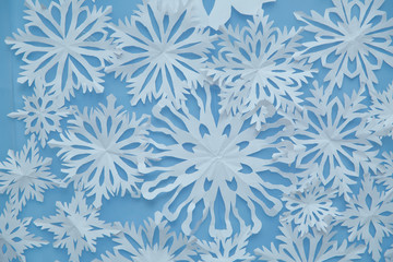 Christmas wallpaper with empty space for text . paper snowflakes blue background . Blue winter holiday background with handmade wooden snowflake .