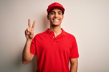 Naklejka premium Young handsome african american man wearing casual polo and cap over red background smiling with happy face winking at the camera doing victory sign. Number two.