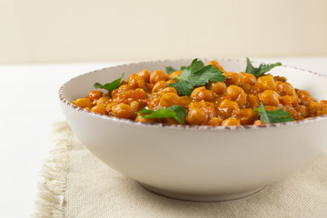 Chana masala in a creamy deep plate on a white background. A traditional dish of Indian cuisine. Close up. Selective focus