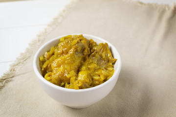 Appetizing Chicken with curry in a cream bowl on a white background. A traditional dish of Indian cuisine.