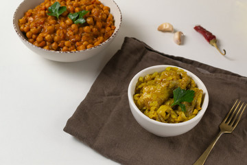Chana masala in a creamy deep plate and chicken with curry on a brown napkin. A traditional dish of Indian cuisine. Selective focus