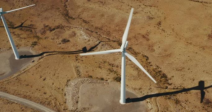 Cinematic aerial view of large wind turbines producing clean sustainable energy
